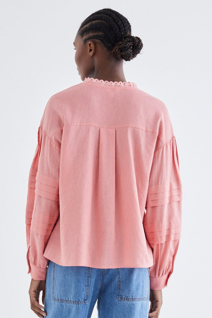 Person wearing a pink top and blue jeans on a white background