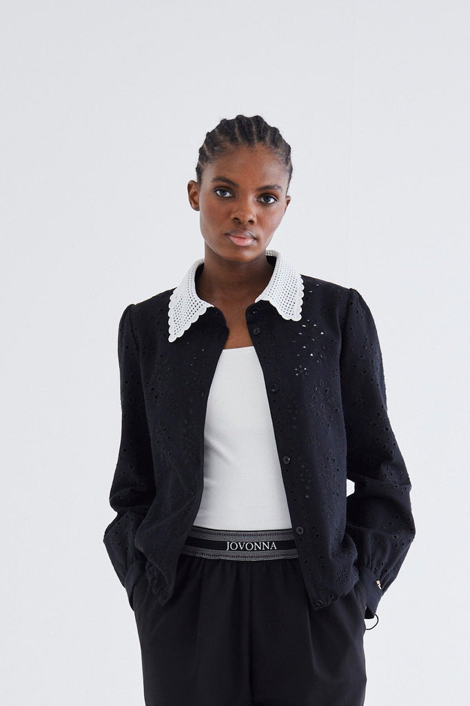 Person wearing a black outfit with a white shirt on a white background